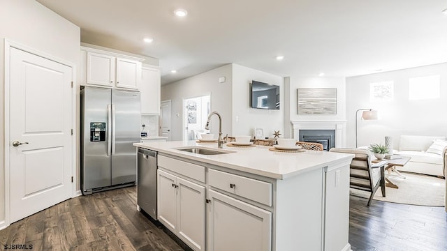 kitchen featuring appliances with stainless steel finishes, dark hardwood / wood-style floors, sink, white cabinets, and a kitchen island with sink