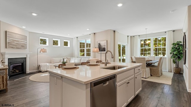 kitchen featuring sink, white cabinets, hanging light fixtures, a kitchen island with sink, and stainless steel dishwasher