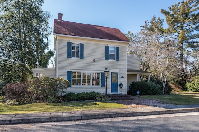 colonial-style house featuring a front lawn