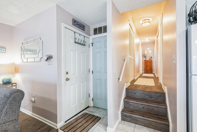 foyer entrance featuring a textured ceiling and light tile patterned floors