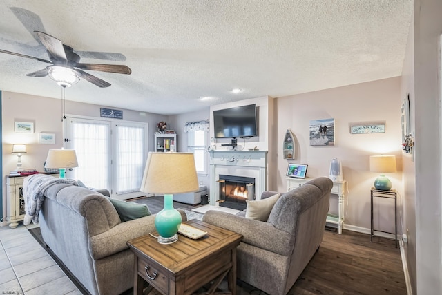 living room featuring ceiling fan, hardwood / wood-style floors, and a textured ceiling