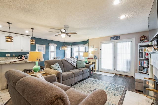 living room featuring ceiling fan, a textured ceiling, and light hardwood / wood-style floors