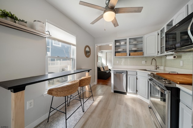 kitchen featuring white cabinetry, appliances with stainless steel finishes, sink, and a kitchen bar