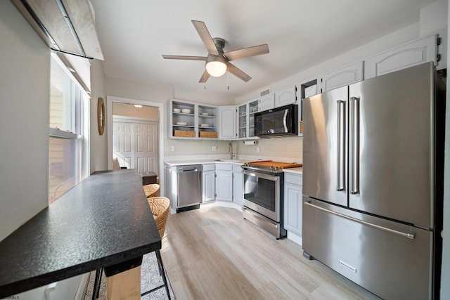 kitchen featuring sink, appliances with stainless steel finishes, white cabinetry, backsplash, and light hardwood / wood-style floors