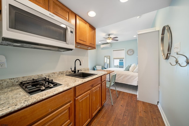 kitchen with sink, dark wood-type flooring, ceiling fan, a wall unit AC, and stainless steel gas cooktop