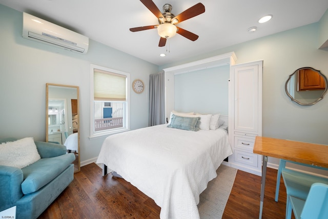 bedroom featuring dark hardwood / wood-style floors, an AC wall unit, ceiling fan, and ensuite bathroom