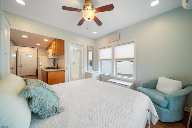 bedroom featuring an AC wall unit, connected bathroom, sink, hardwood / wood-style flooring, and ceiling fan