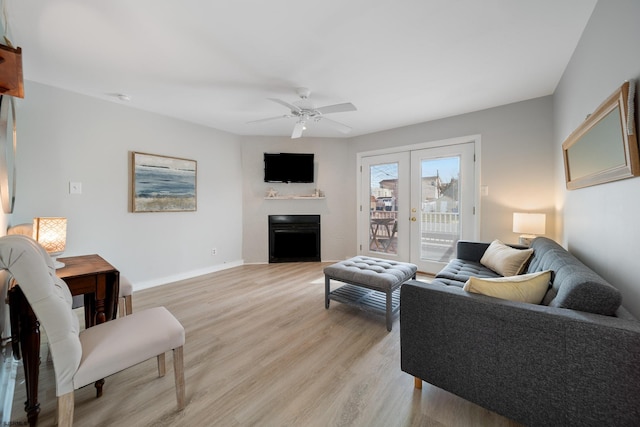 living room featuring french doors, ceiling fan, and light wood-type flooring