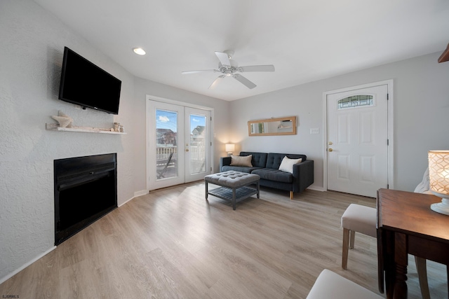 living room featuring french doors, ceiling fan, and light wood-type flooring