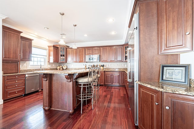 kitchen with a kitchen island, decorative light fixtures, a kitchen bar, stainless steel appliances, and dark wood-type flooring