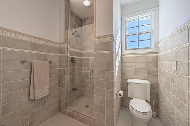 bathroom with a shower with door, tile walls, and toilet