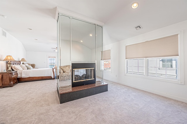 carpeted bedroom featuring multiple windows, vaulted ceiling, and a multi sided fireplace