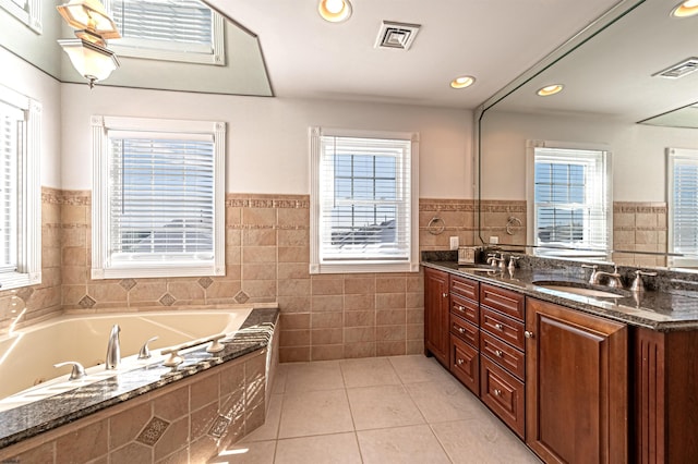 bathroom with a healthy amount of sunlight, tile walls, tile patterned floors, and tiled bath