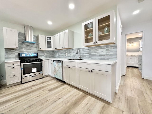 kitchen featuring sink, white cabinets, stainless steel appliances, wall chimney range hood, and light wood-type flooring