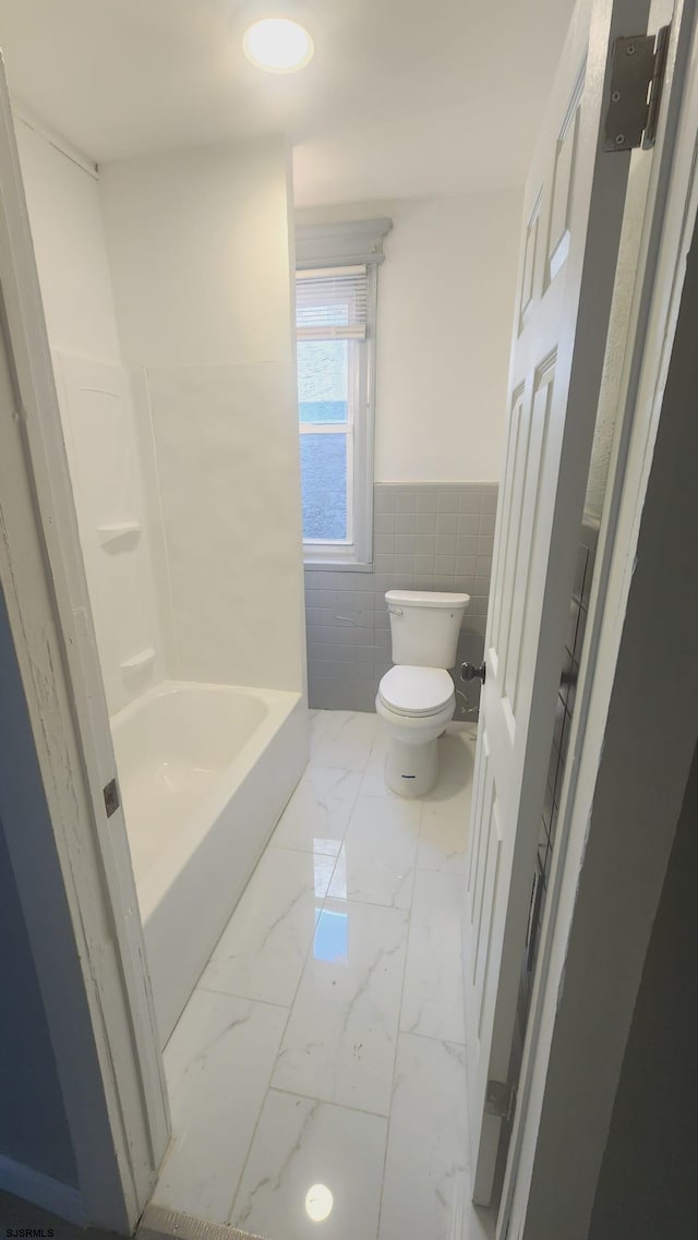 bathroom with tile walls and toilet