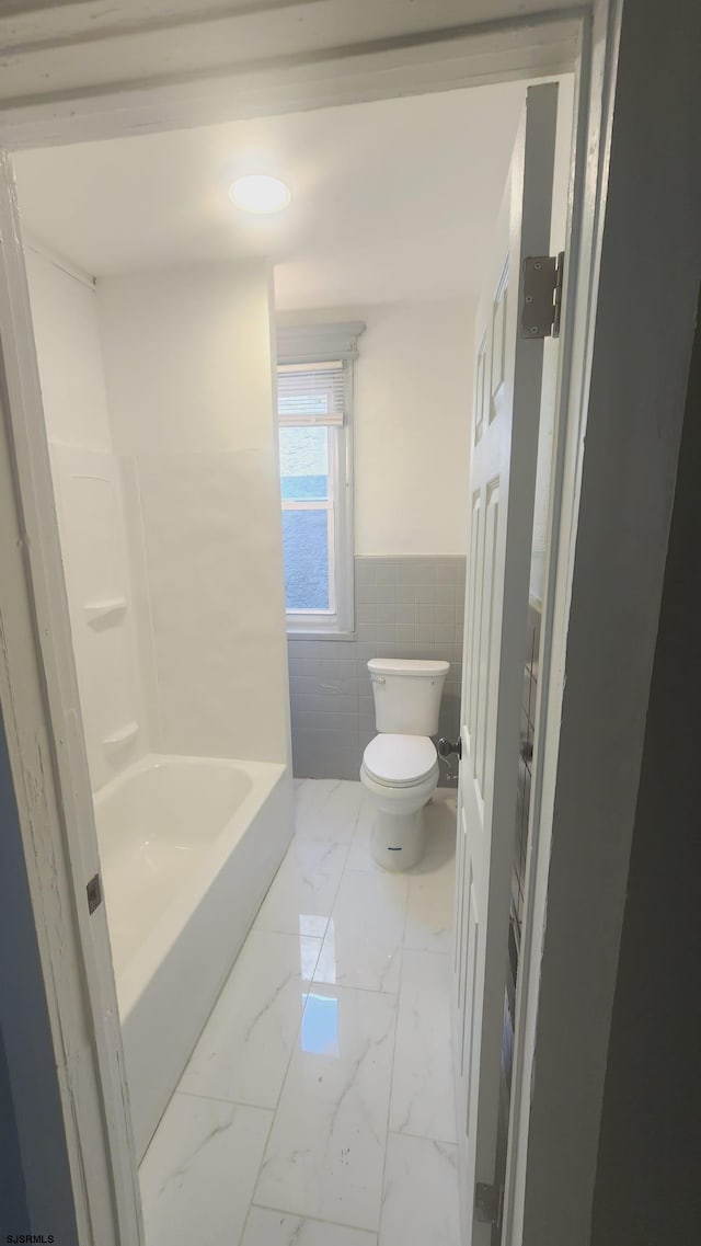 bathroom with tile walls and toilet