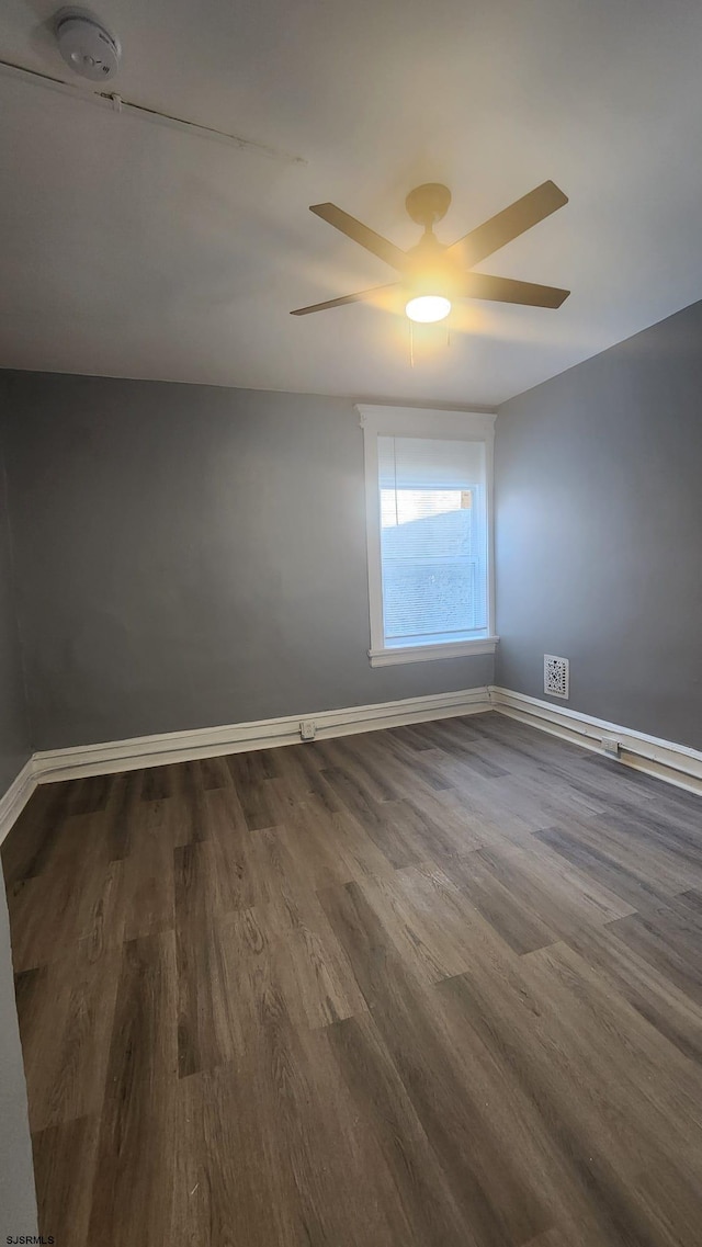 unfurnished room featuring dark wood-type flooring and ceiling fan