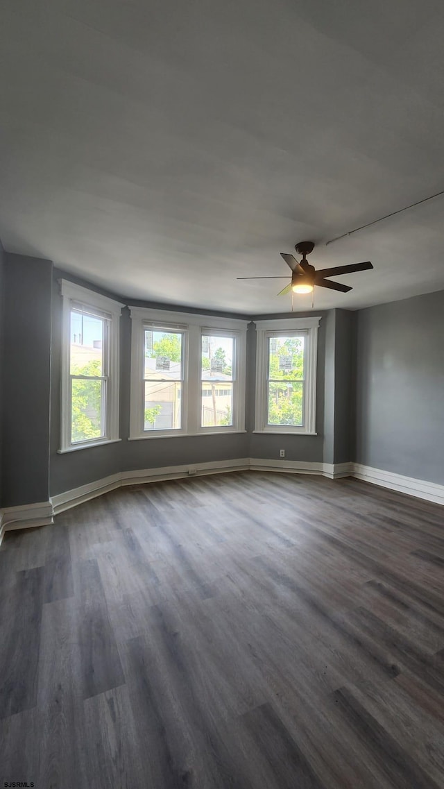 unfurnished room featuring plenty of natural light, dark hardwood / wood-style floors, and ceiling fan