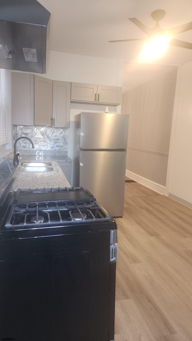 kitchen with sink, light wood-type flooring, appliances with stainless steel finishes, white cabinets, and backsplash