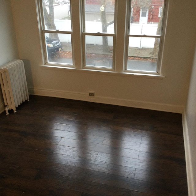 spare room featuring radiator heating unit and dark hardwood / wood-style flooring