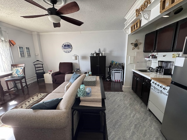 living room with sink, crown molding, a textured ceiling, and ceiling fan