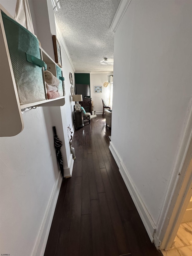 hallway with crown molding, dark wood-type flooring, and a textured ceiling