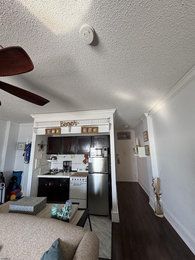 kitchen with dark brown cabinets, a textured ceiling, ornamental molding, appliances with stainless steel finishes, and dark hardwood / wood-style flooring