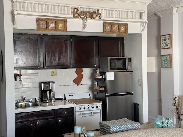 kitchen with tasteful backsplash, appliances with stainless steel finishes, sink, and dark brown cabinets