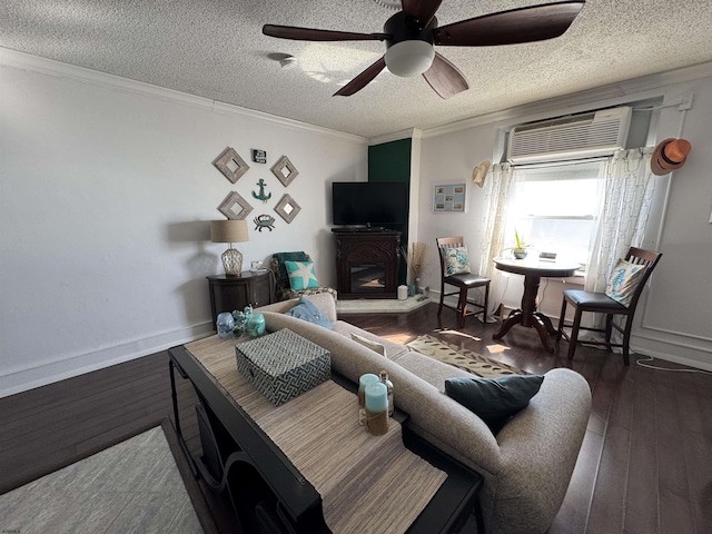 living room featuring an AC wall unit, dark hardwood / wood-style floors, ceiling fan, crown molding, and a textured ceiling