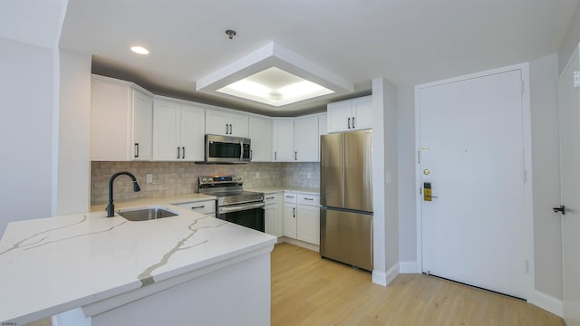 kitchen featuring sink, white cabinets, light stone counters, stainless steel appliances, and light wood-type flooring