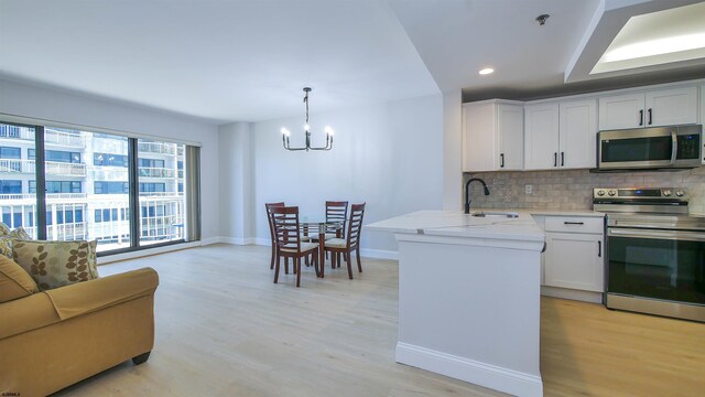 3101 Boardwalk Unit 1512-2, Chelsea Heights, NJ 08401 - kitchen featuring appliances with stainless steel finishes, pendant lighting, white cabinetry, sink, and backsplash