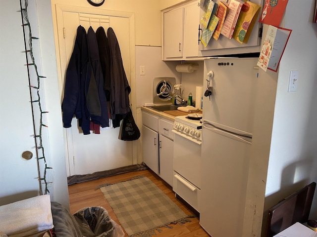 kitchen with white cabinetry, white appliances, and light hardwood / wood-style floors