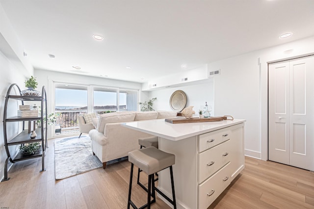 interior space with white cabinetry, a kitchen island, a breakfast bar area, and light hardwood / wood-style flooring