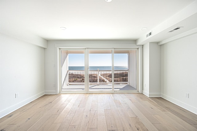 unfurnished room featuring a water view and light hardwood / wood-style floors