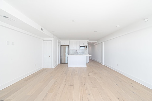 unfurnished living room with sink and light hardwood / wood-style floors