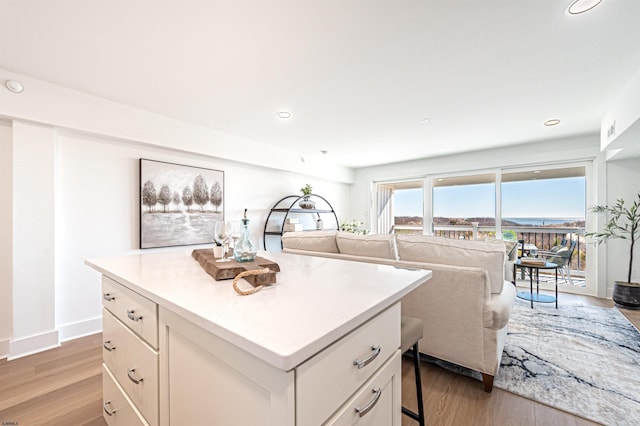 kitchen with white cabinetry, a kitchen island, a kitchen breakfast bar, and light wood-type flooring