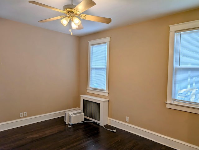 unfurnished room featuring an AC wall unit, dark hardwood / wood-style floors, radiator heating unit, and ceiling fan