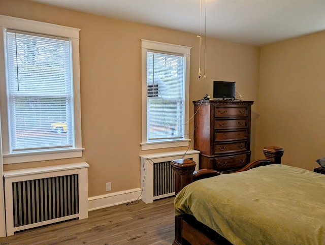 bedroom with hardwood / wood-style floors and radiator heating unit