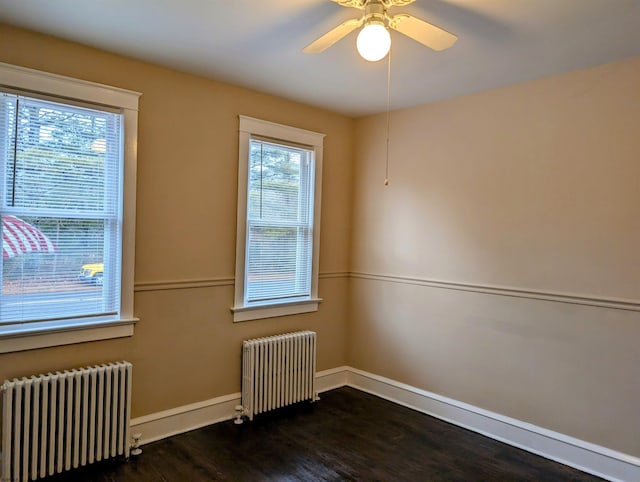 empty room with ceiling fan, radiator, and dark hardwood / wood-style floors