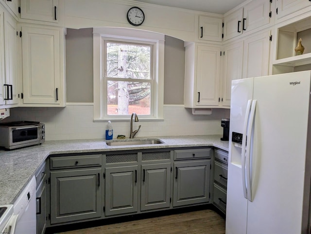 kitchen with sink, gray cabinetry, backsplash, light stone counters, and white appliances