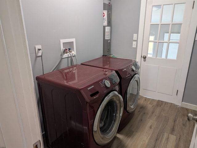 laundry room featuring water heater, light hardwood / wood-style flooring, and independent washer and dryer