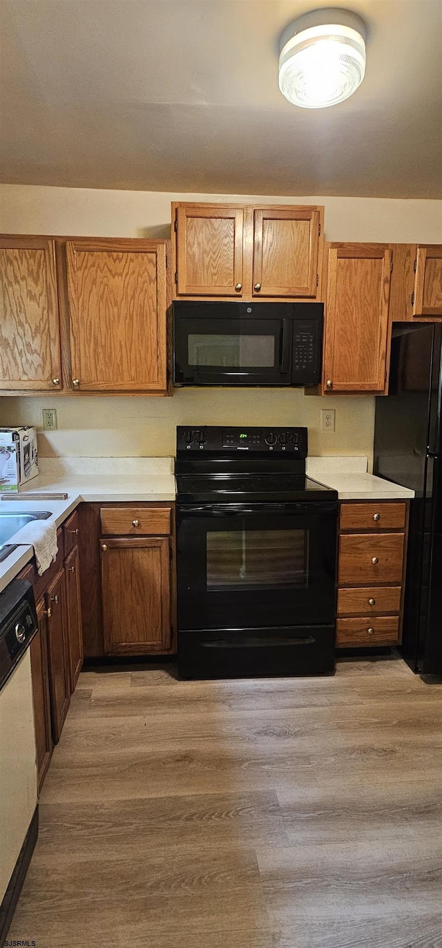 kitchen featuring sink, light hardwood / wood-style floors, and black appliances