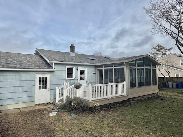 rear view of house featuring a yard, a deck, and a sunroom