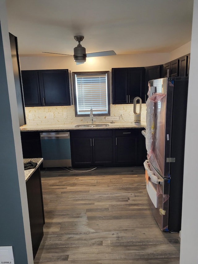 kitchen with light stone countertops, sink, dishwasher, fridge, and decorative backsplash