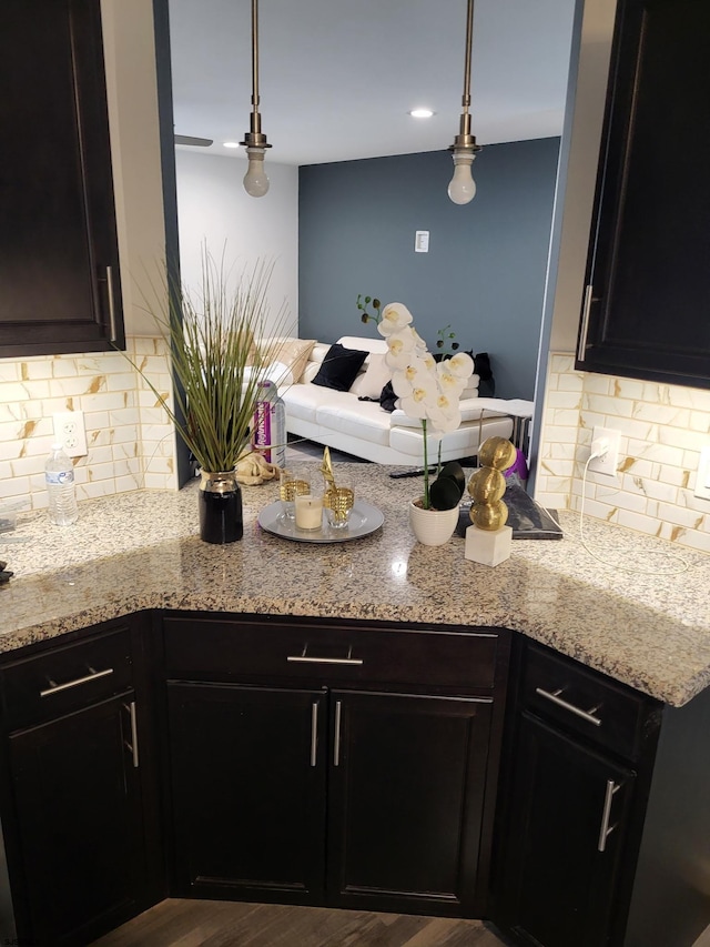 kitchen featuring hardwood / wood-style flooring, decorative light fixtures, tasteful backsplash, and light stone countertops