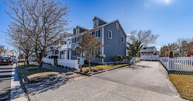 view of front of house with a residential view, fence, and aphalt driveway