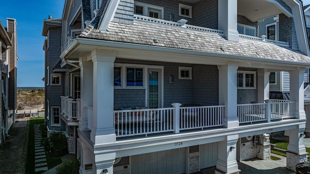 back of property with covered porch, a garage, and a balcony