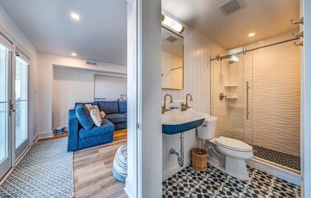 bathroom with hardwood / wood-style flooring, sink, a shower with shower door, and toilet