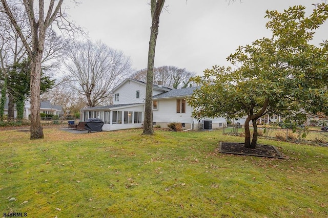 back of house featuring a lawn, a sunroom, and central AC