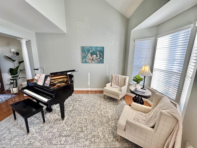 sitting room with vaulted ceiling, ornate columns, and hardwood / wood-style floors